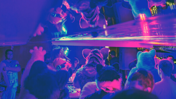People dancing infront of a DJ booth, with a mirrored ceiling reflecting them