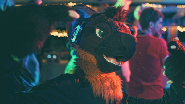 A partygoer poses in silent-disco headphones on their fursuit's head
